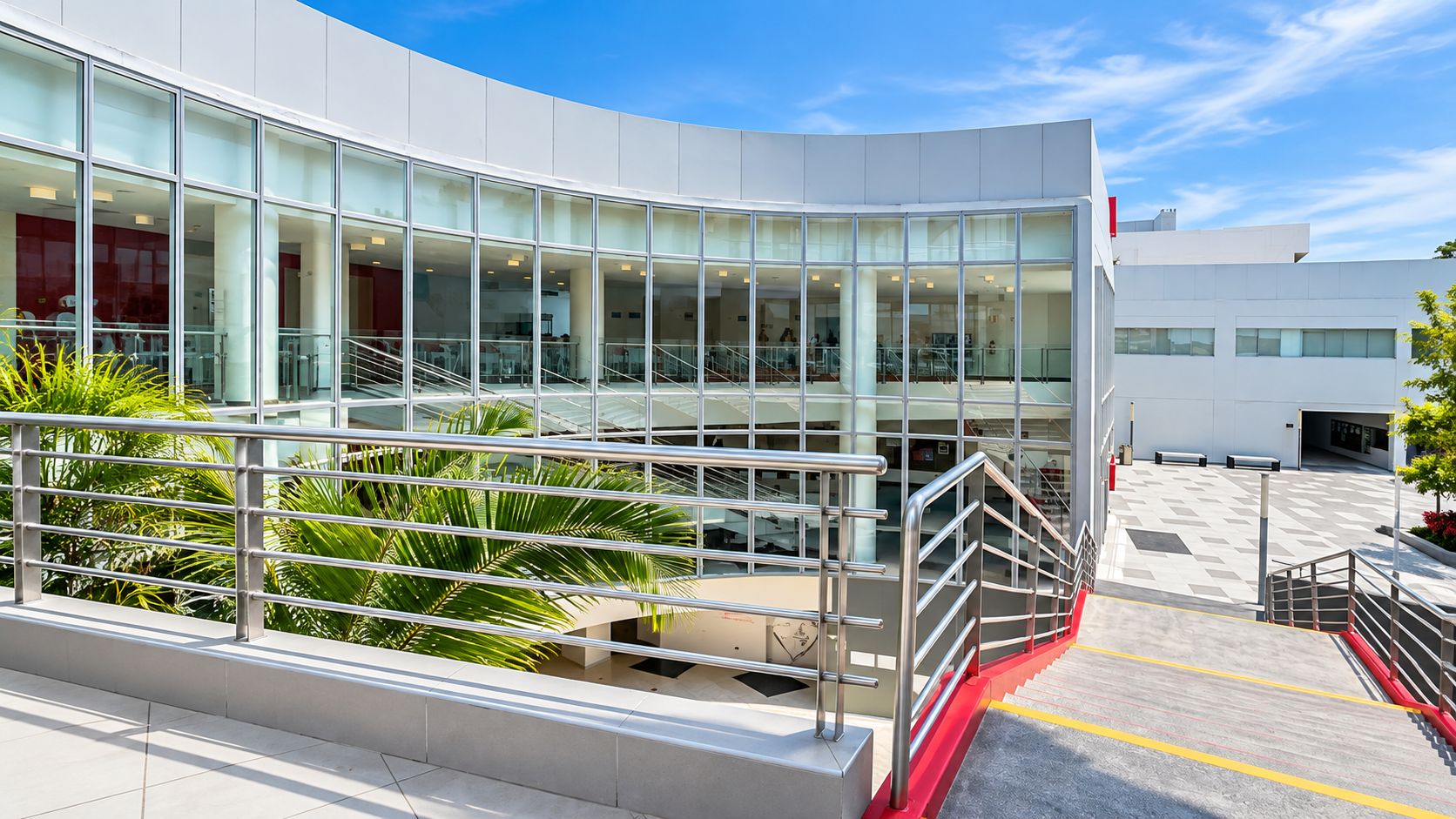 Edificio con fachada curva de vidrio y escalera exterior con barandas de acero inoxidable.