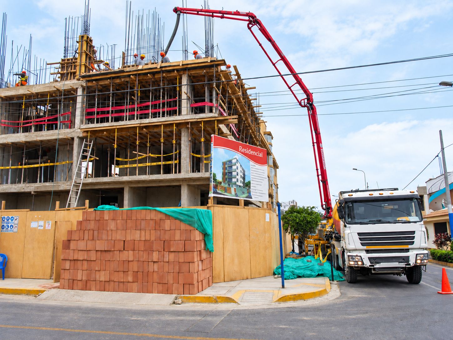 Edificio de varios niveles en construcción, con encofrados y una bomba de concreto trabajando desde la calle.